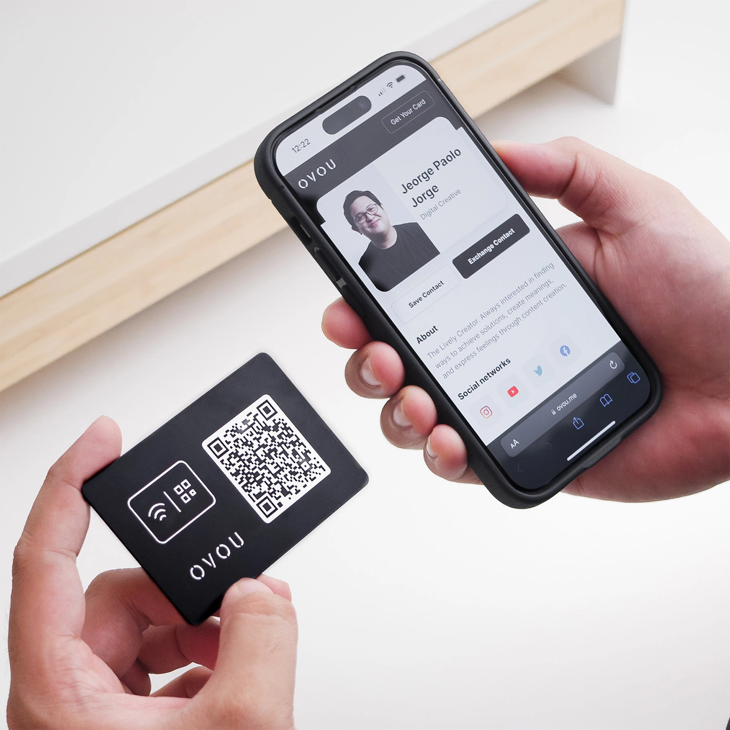 Guy holding OVOU smart business card on left hand with QR facing up and Smartphone on the right hand with OVOU digital business profile on screen.
